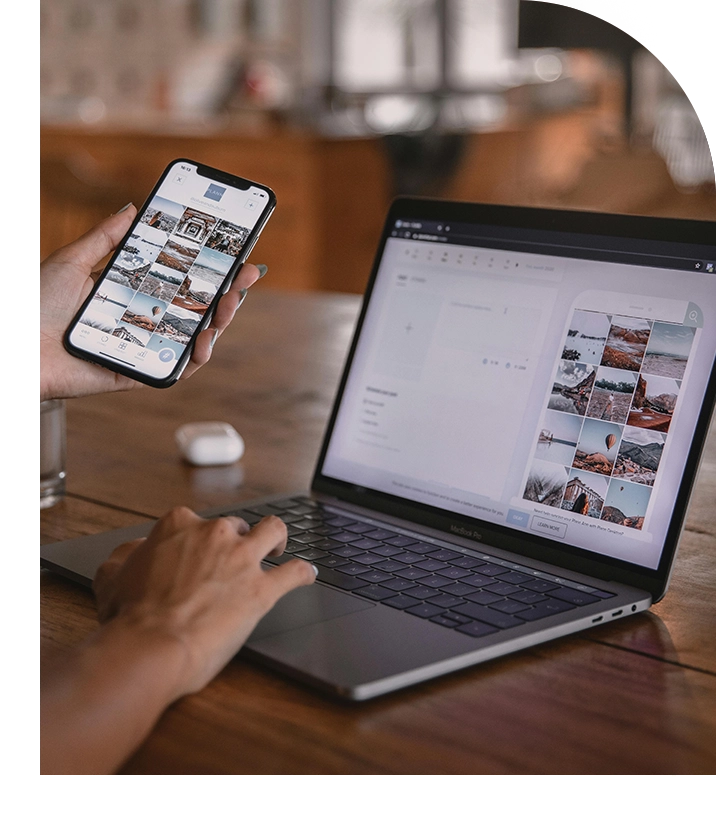 Person using laptop and phone on desk.