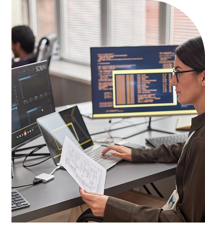 Woman working at desk with laptop and documents.